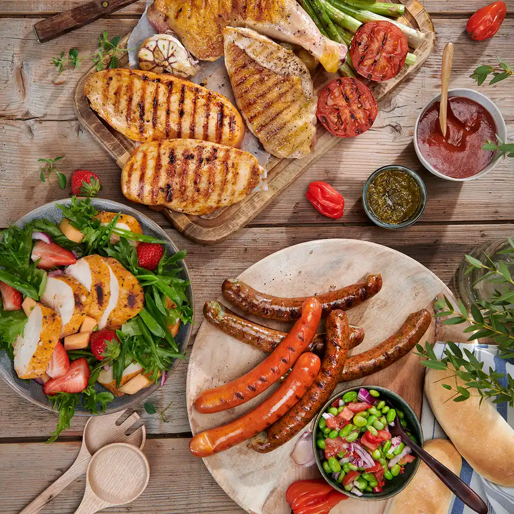 Matfoto med grillede pølser og tilbehør på et bord